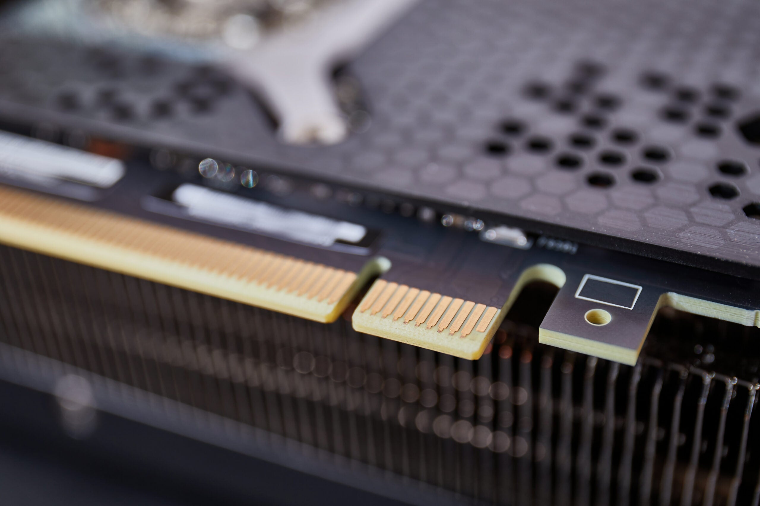 PCIe connector detail on a high-end graphics card with metal backplate heatsink